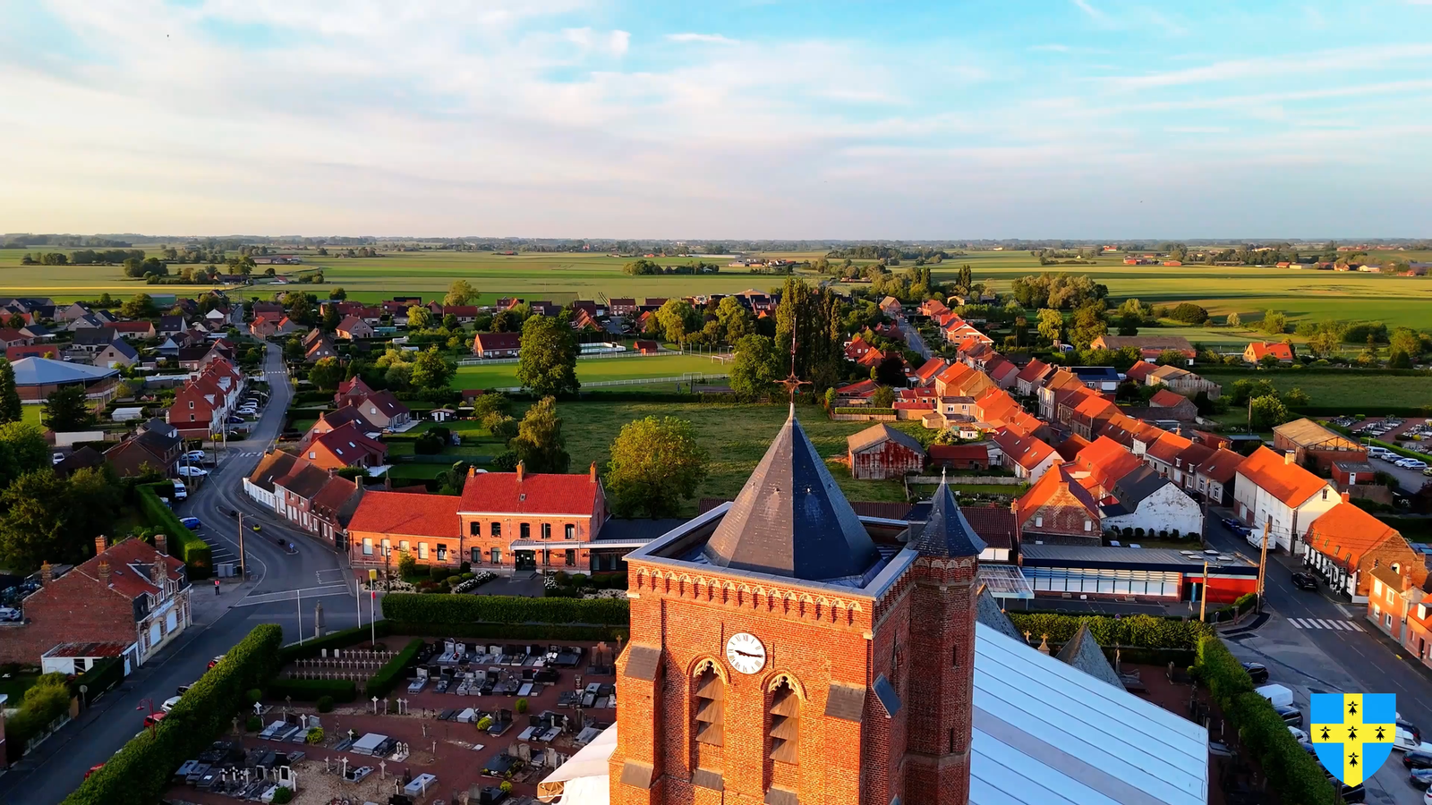 Fête de la musique à Arnèke : vue aérienne par drone du clocher de l'église Saint-Martin, du bourg et de la plaine flamande